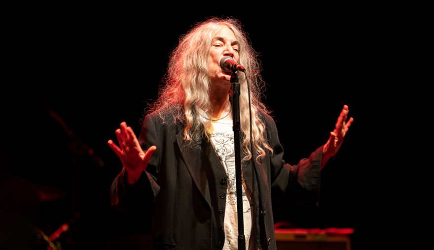 Patti Smith performs on stage under a spotlight