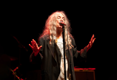 Patti Smith performs on stage under a spotlight