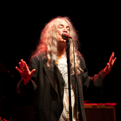 Patti Smith performs on stage under a spotlight