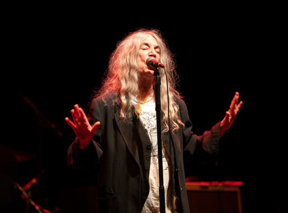 Patti Smith performs on stage under a spotlight
