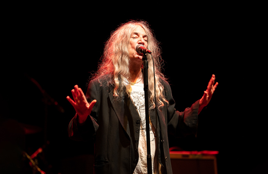 Patti Smith performs on stage under a spotlight