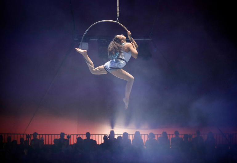 Aerial acrobat performing in a dark circus tent