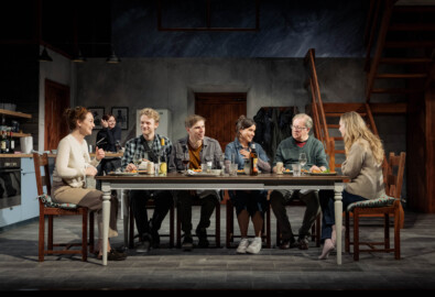 Reunion cast sits at table on the stage