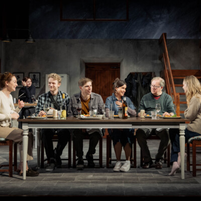 Reunion cast sits at table on the stage