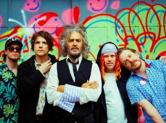 The Flaming Lips band members in front of a colourful wall