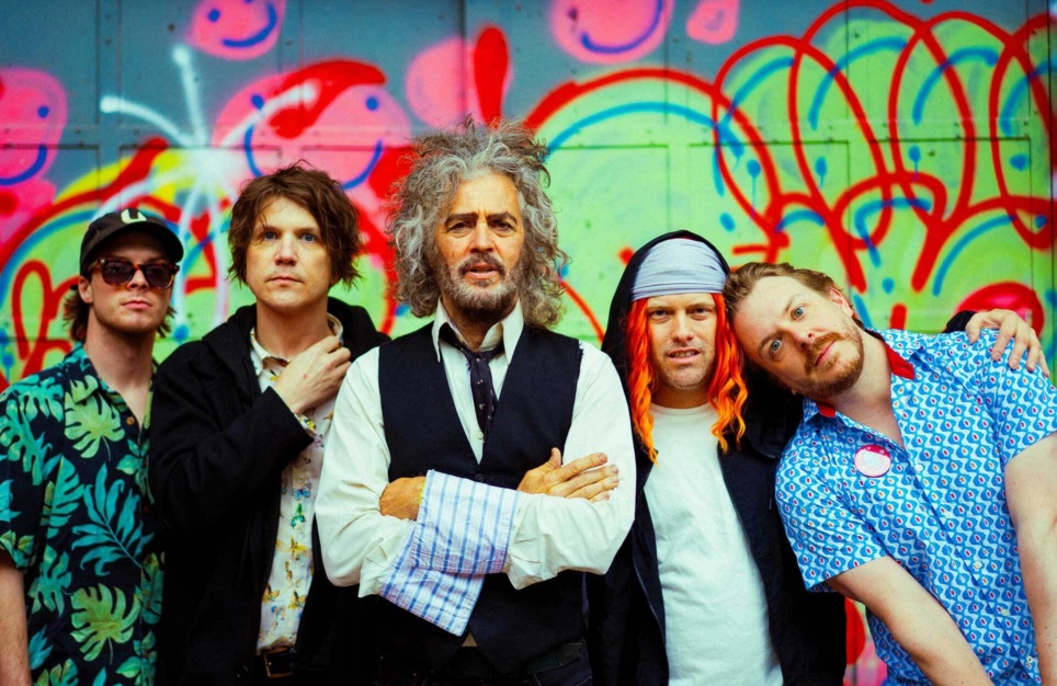 The Flaming Lips band members in front of a colourful wall